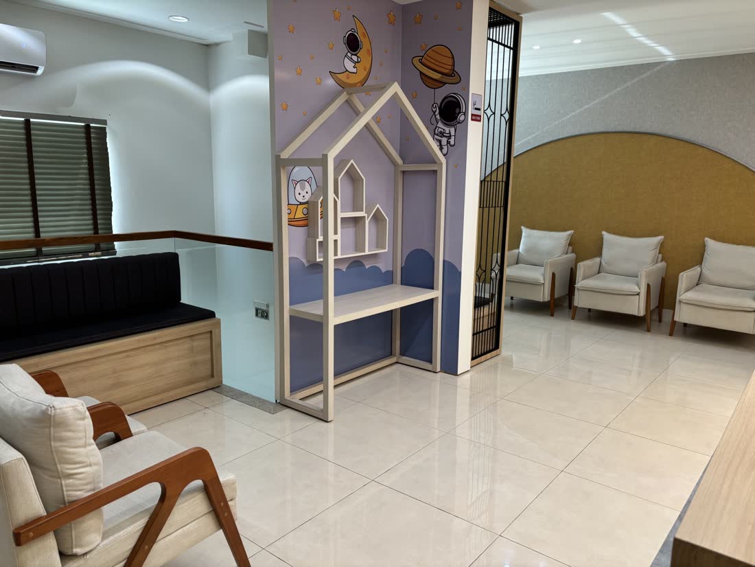 Sala de espera da clínica, com poltronas e espaço infantil